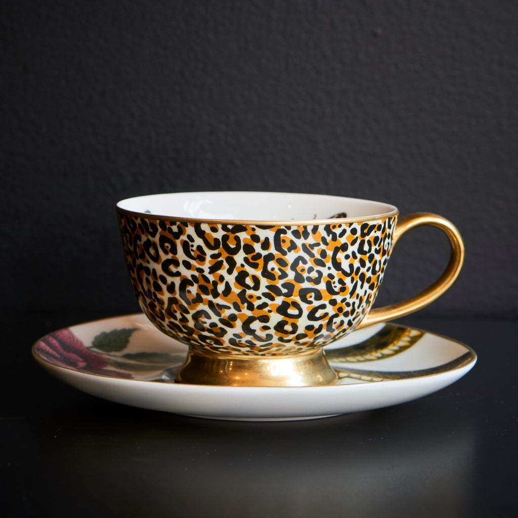 Cup with leopard print design on a saucer against a snake and floral background.